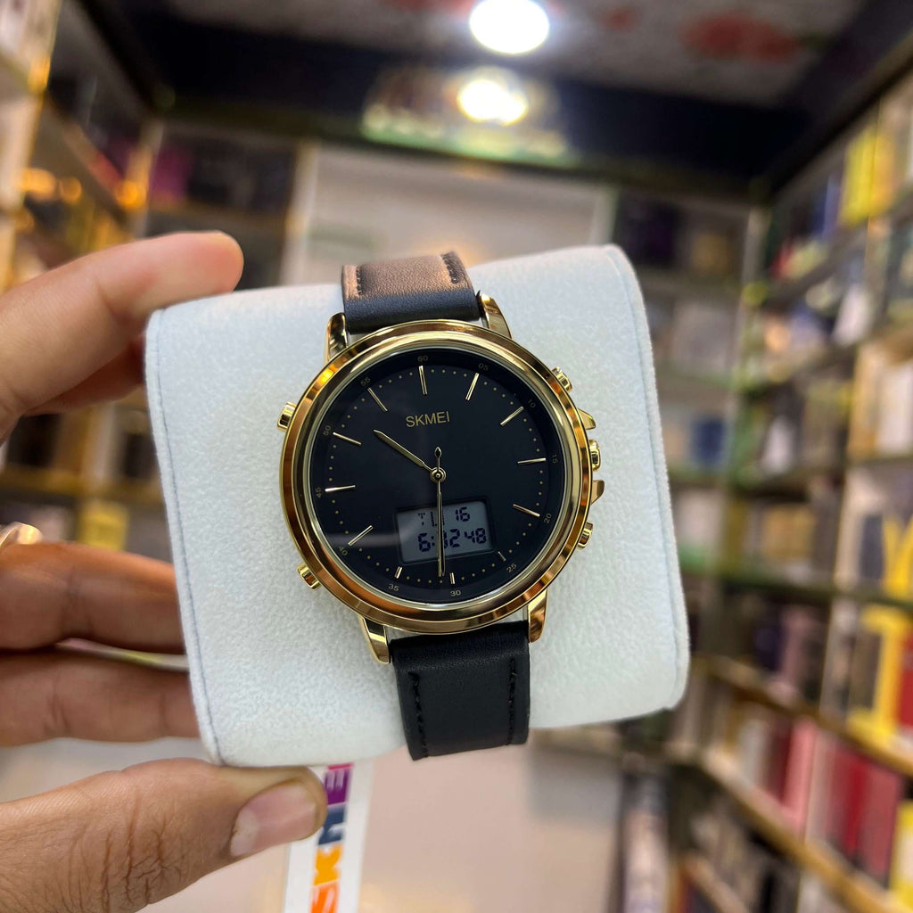 Gold and black watch on a white cushion with a blurred bookshelf background
