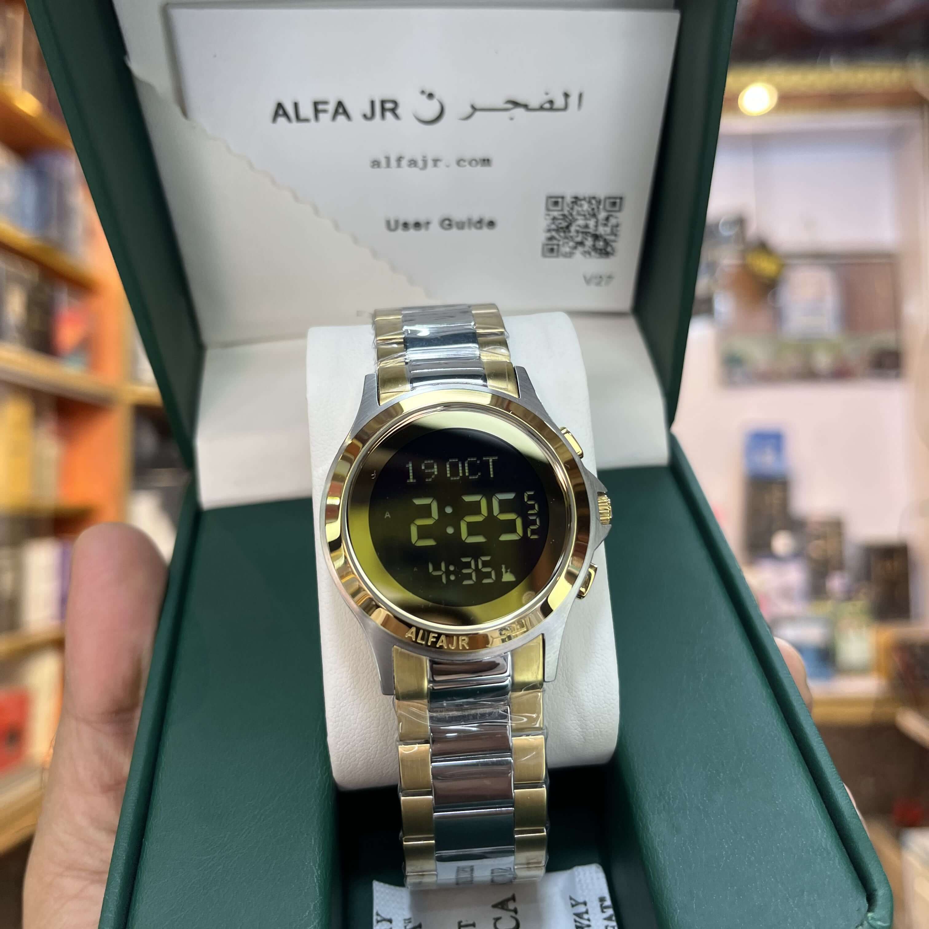 Gold and silver watch with digital display in a green box