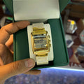 Gold and white digital watch held in a green box