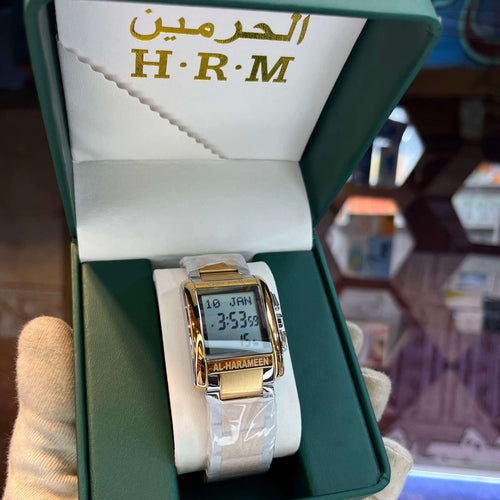 Gold digital watch in a green box with 'H.R.M' branding.