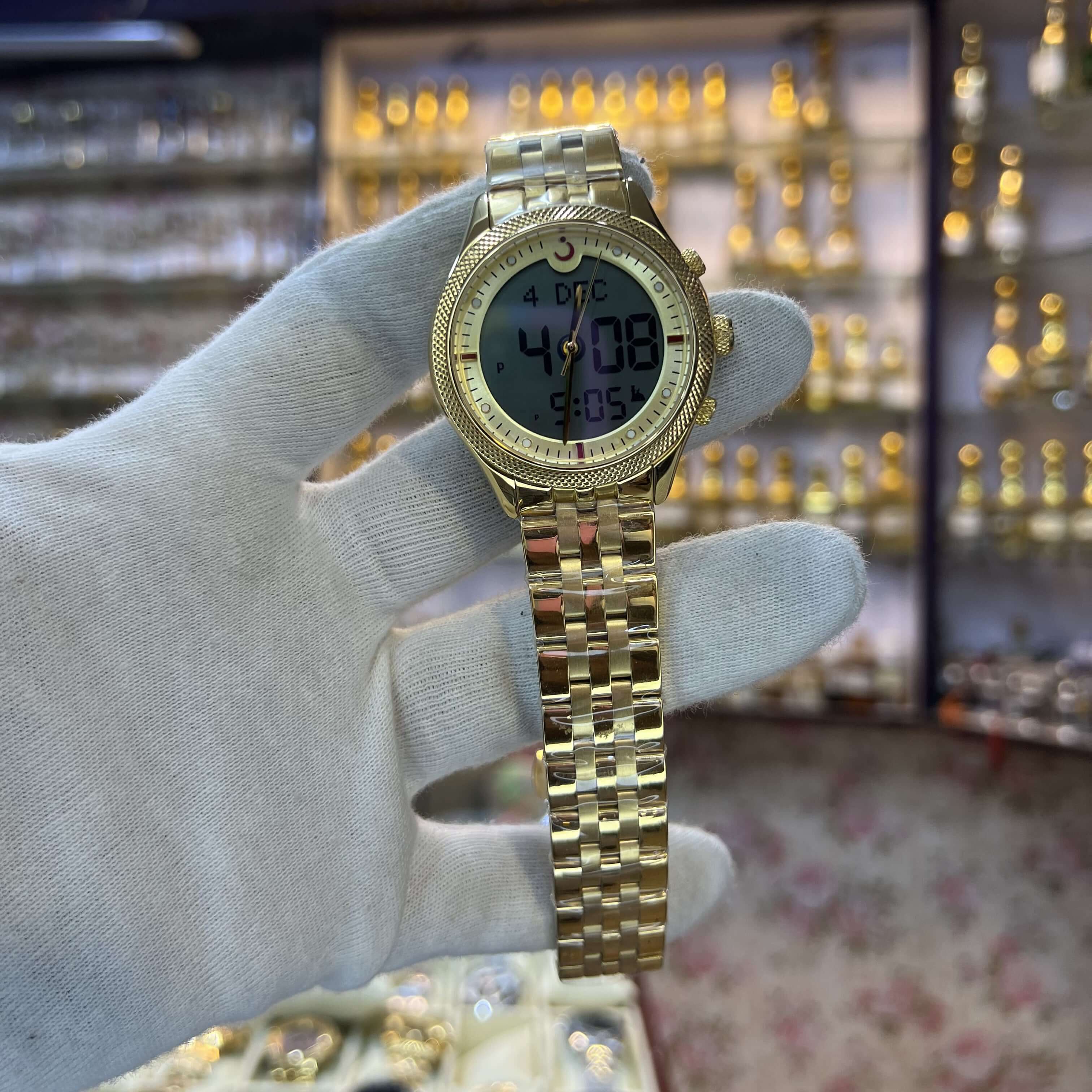 Gold wristwatch held by a gloved hand 