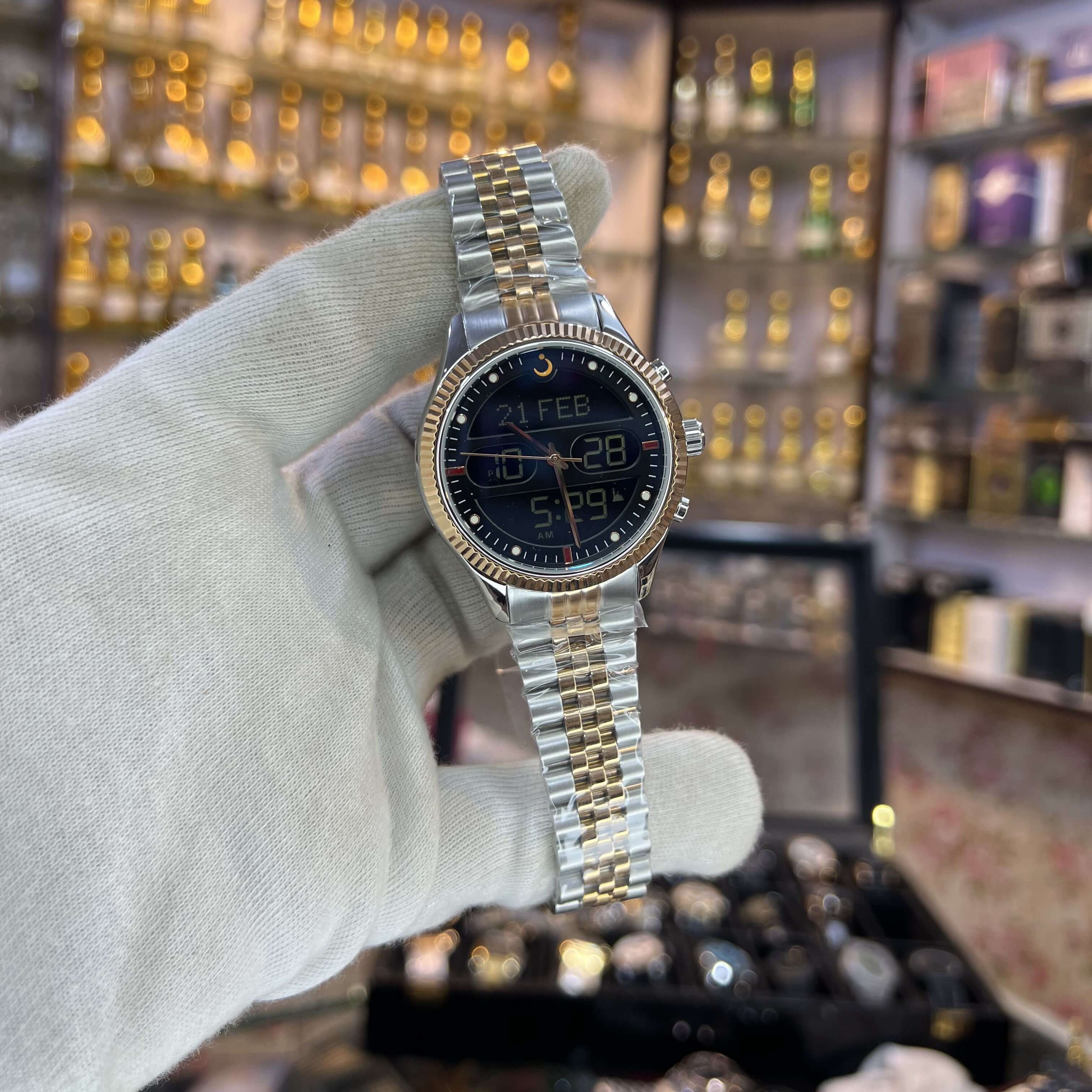 Silver watch held by a gloved hand with a jewelry store background