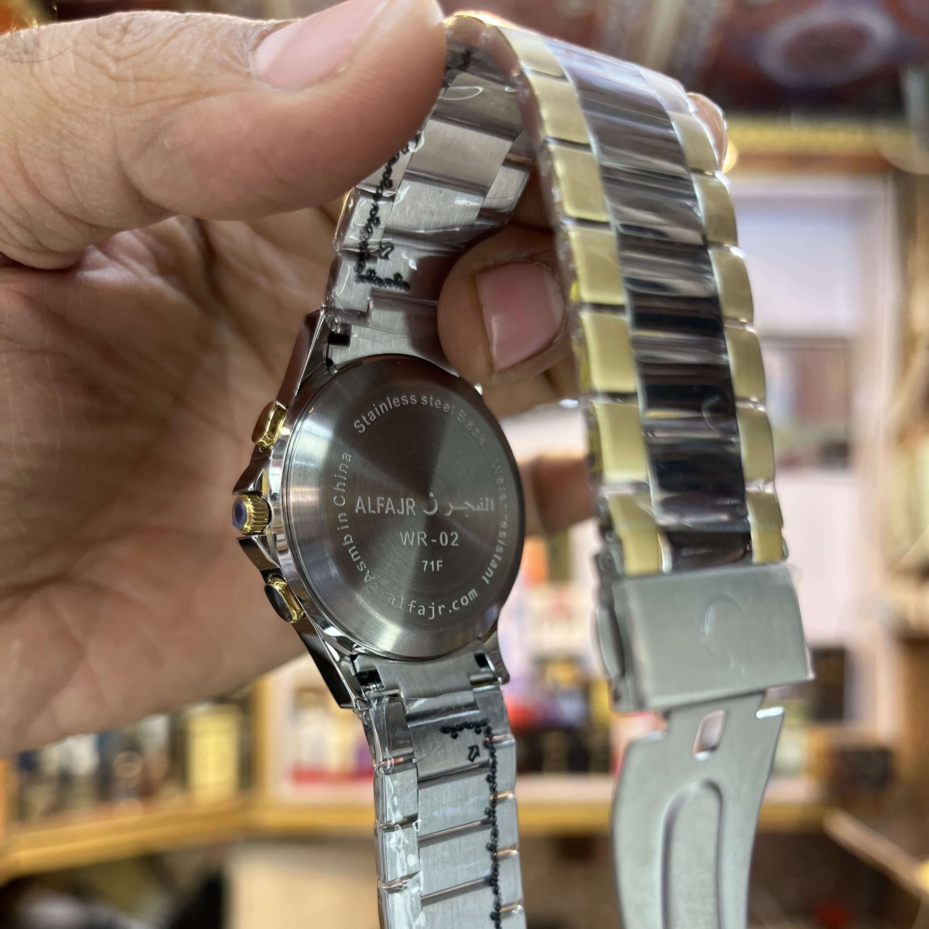 Silver watch with a detailed band held by a hand 