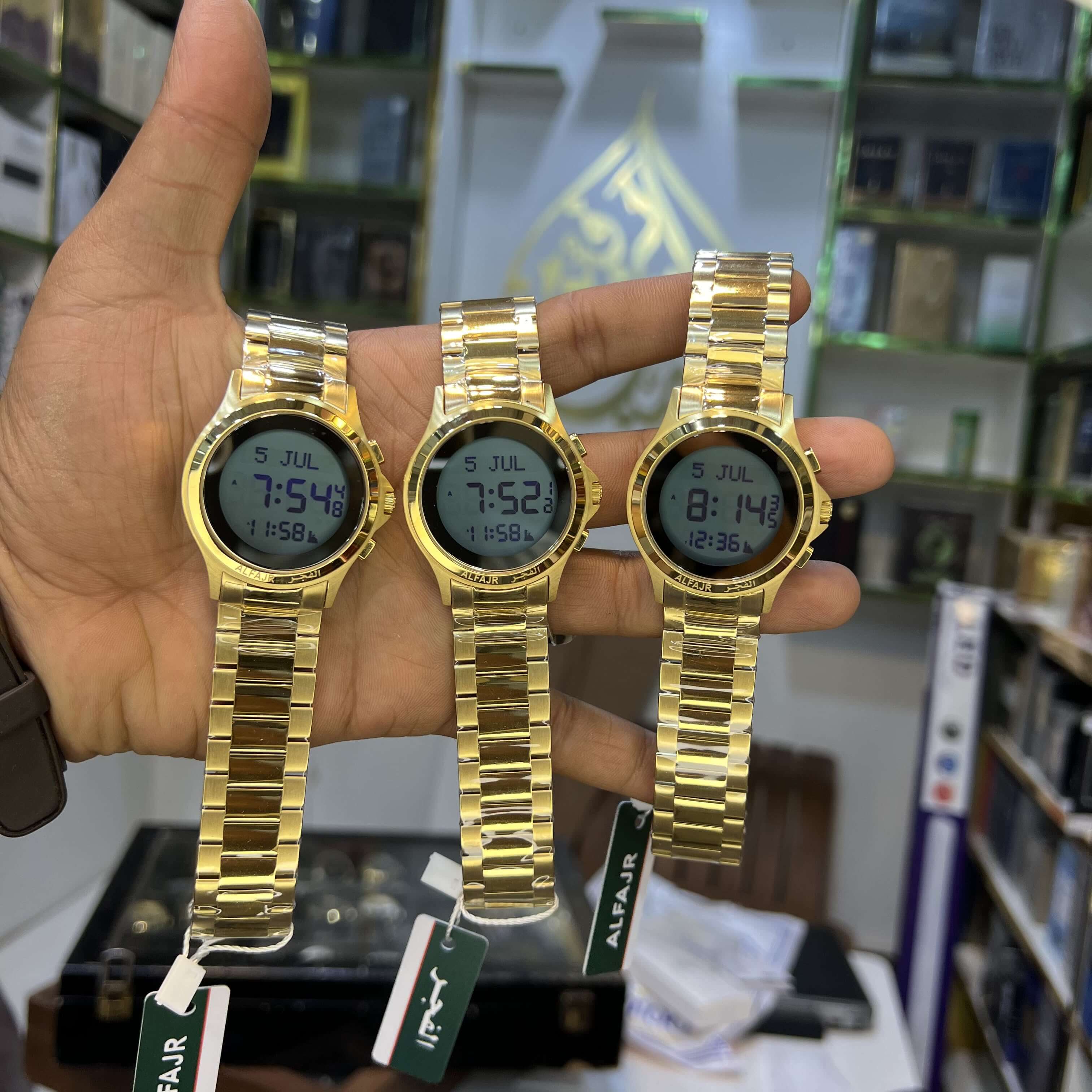 Three gold digital watches held in a hand with a blurred background