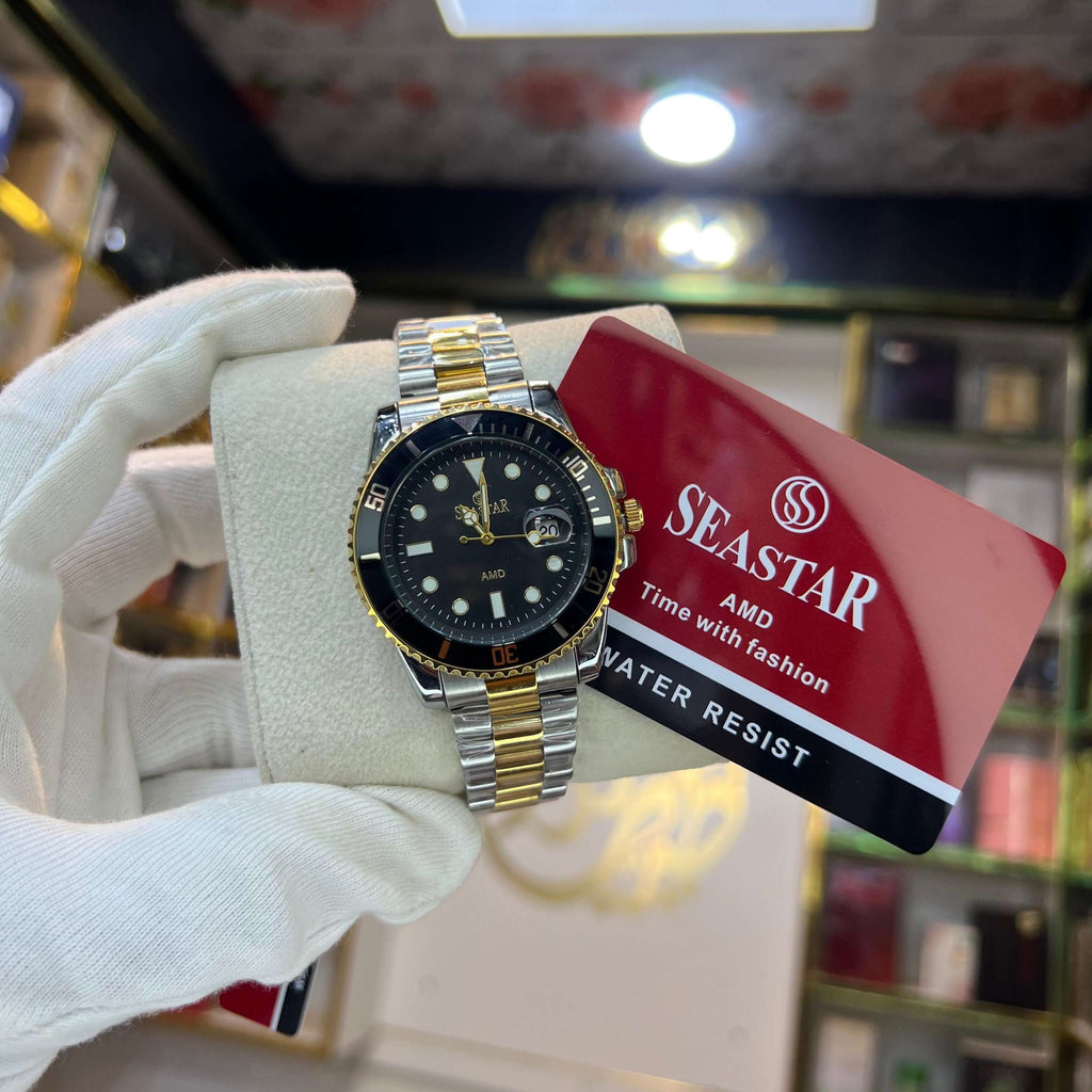 Gold and silver watch held by a gloved hand with a Seastar card in the background