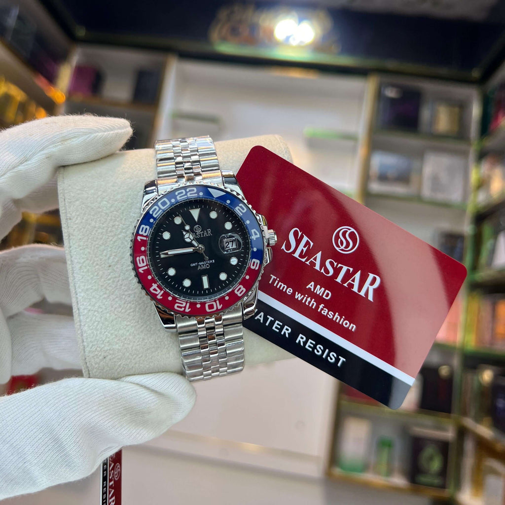 Seastar watch with a red and blue  bezel held by a gloved hand, with a Seastar card in the background.